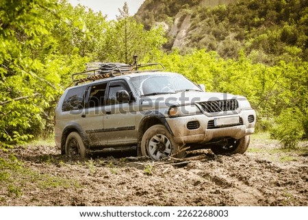 SUV 4WD grey car stuck in muddy off-road. Closeup the wheel rotates in the mud. Adventure travel Vashlovani safari tour Royalty-Free Stock Photo #2262268003