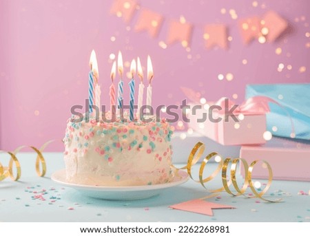 Festive cake with candles on the background of festive pink wall with gifts and flags in serpentine