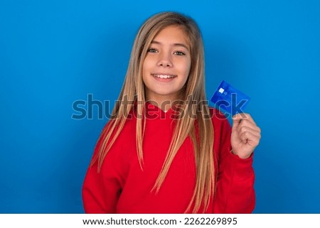 Photo of happy cheerful smiling positive beautiful caucasian teen girl wearing red sweater over blue wall recommend credit card