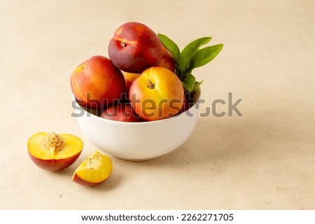 Whole nectarine peaches, fresh red fruits in a bowl. Neutral background. Royalty-Free Stock Photo #2262271705