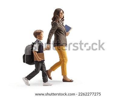 Full length profile shot of a teacher and a schoolboy walking and holding hands isolated on white background