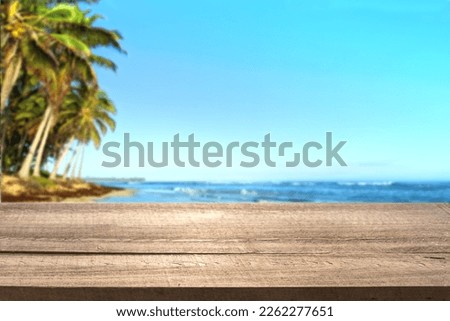Wooden desk of free space and tropic sea coast landscape with coconut palms. Summer sunny sea, blue sky and wooden table top. Tropic background for display products.
