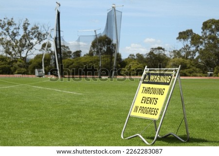 A yellow warning sign for field events at an sporting or atheletics carnival or competition. Exercise caution around throwing events such as javelin, shot-put, discus and hammer throw. 