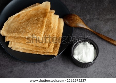 Stack of russian thin pancakes blini with fresh sour cream