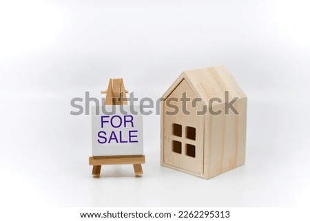 Model house with for sale sign on a plain white background. No people. Copy space. Housing market concept. 