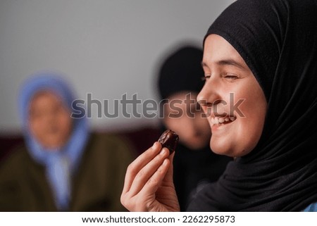 Happy Muslim family having iftar dinner during Ramadan smiling child girl eating dates to break fast eid mubarak. Royalty-Free Stock Photo #2262295873