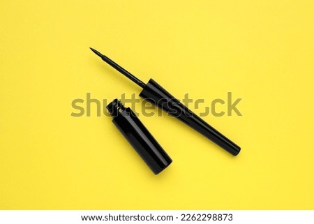 Black eyeliner on yellow background, flat lay. Makeup product Royalty-Free Stock Photo #2262298873