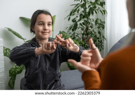 Small Caucasian teen girl child do articulation exercises with caring mother or teacher at home. Little kid pronounce sounds speak talk with tutor or coach, engaged in voice pronunciation together Royalty-Free Stock Photo #2262305379