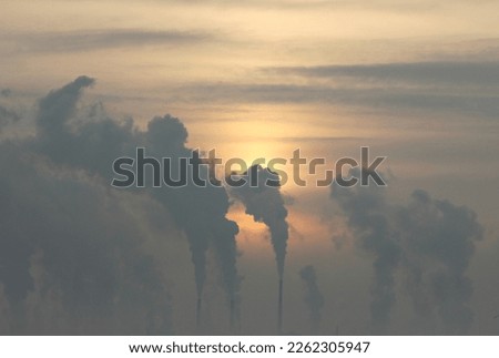 silhouettes of smoking factory chimneys against the background of the rising sun