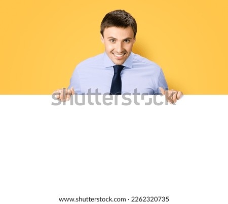 Portrait image of business man professional bank manager in confident cloth. Businessman stand behind hang over empty white banner signboard with copy space. Isolated orange yellow background