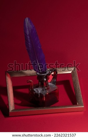 Fountain pen and old ink pot on an vintage red background . Old history background with golden photo frame.