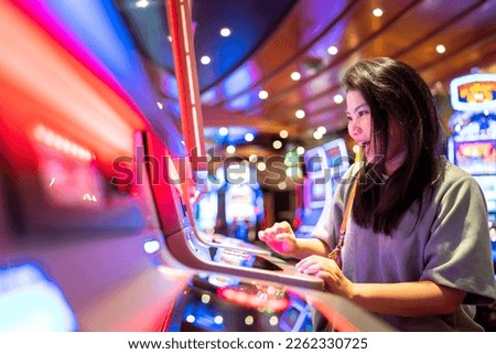exited asia female woman slot machine gambling cheerful smile hand pressing bet button in casino club entertainment concept,exited asian woman hand play slot machine in casino hotel Royalty-Free Stock Photo #2262330725