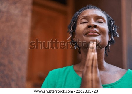 Middle age african american woman smiling confident praying at street