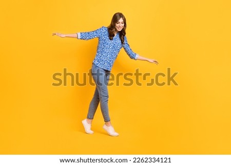 Full size profile photo of pretty satisfied girl carefully walk balancing empty space rope isolated on yellow color background