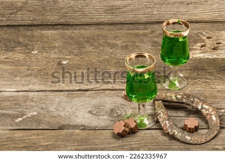 St. Patrick's Day concept. Traditional green cocktail, sweet chocolate in the shape of clover leaves, horseshoe, vintage rope. Traditional festive decor, wooden background, copy space