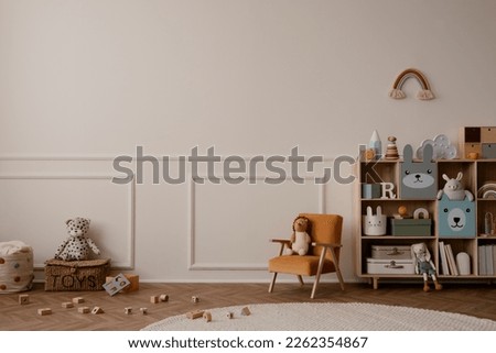 Creative composition of kids room interior with copy space, wooden sideboard, orange armchair, rainbow on the wall, round rug, toys, wooden block and personal accessories. Home decor. Template. 