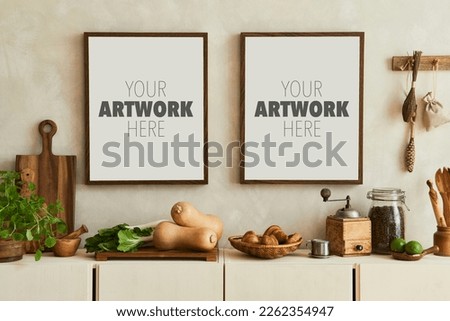 Stylish composition of modern kitchen interior design with mock up poster frames, beige sideboard, vegetables and retro accessories. Template. Autumn vibes.