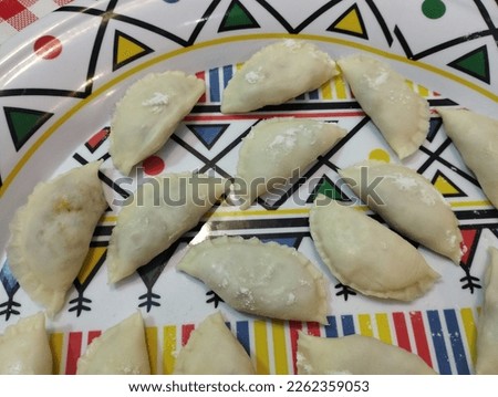 A picture of raw curry puffs pastry which are preparing for frying. Top view of raw curry puffs in a beautiful serving tray. Image is a selective focus.