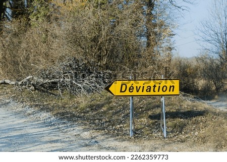 Deviation sign on the forest gravel road in a France shows to left.