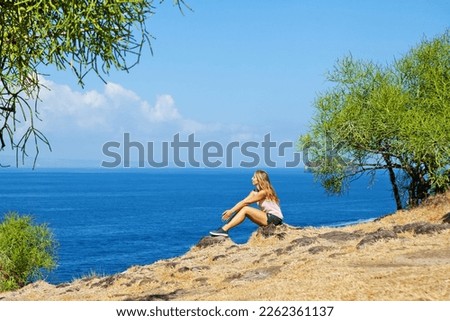 Happy woman walking on summer sea beach holiday. Beautiful girl relaxing on high ocean cliff. Looking at beautiful sky and sea. Healthy family lifestyle, summer travel on tropical island.