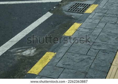 black yellow line on the edge of the sidewalk used as a vehicle boundary marker