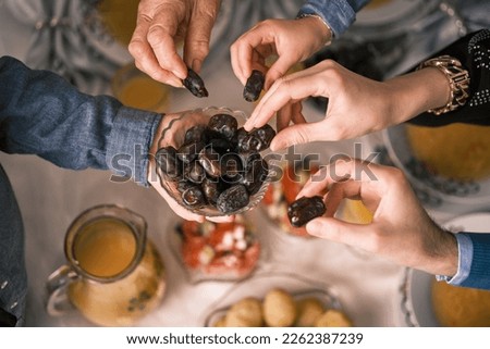 Happy Muslim family having iftar dinner to break fasting during Ramadan dining table at home group of people eating a healthy food dates. Royalty-Free Stock Photo #2262387239