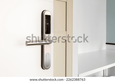Open front door with electronic mortise lock and handle. The door is opened with a combination of a digital code or a plastic card. Modern door opening and property security systems. Royalty-Free Stock Photo #2262388763