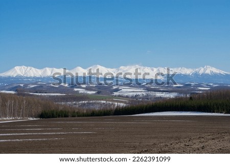Upland field where snow remains and snowy mountains
