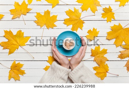 Female hands holding cup of coffee on wooden table.
