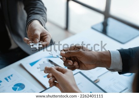 A group of Asian businessmen holding a jigsaw together are meeting the office. They are meeting on finance and managing business policies perfectly according to the model and laid out the plan. Royalty-Free Stock Photo #2262401111