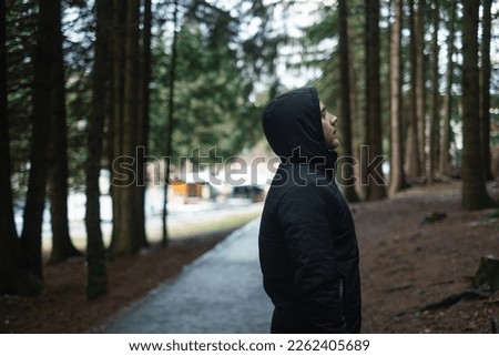 Portrait of a hiker walking along a path in the forest. Strong athletic traveling man on the background of the forest.