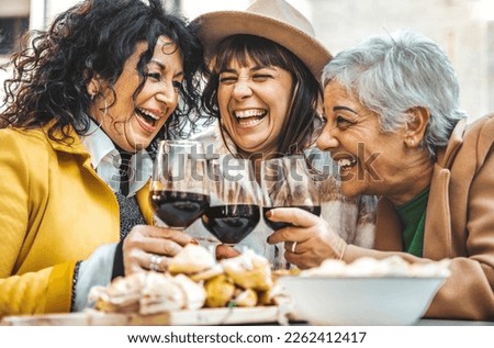 Happy senior women drinking red wine at bar restaurant - Mature people having fun hanging out on city street - Life style concept with older friends smiling and laughing together Royalty-Free Stock Photo #2262412417