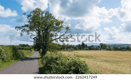 The John Muir Way walking trail using national cycle route 7 on  quiet country lanes heading east from Loch Lomond towards Croftamie, Central Scotland. Royalty-Free Stock Photo #2262417249