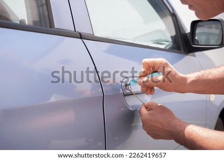 Locksmith opening a locked car door Royalty-Free Stock Photo #2262419657