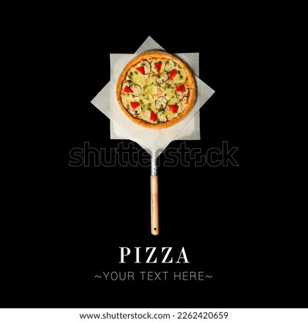 Top view of Italian uncut veggie pizza with zucchini, mozzarella cheese, aubergine, bell pepper, pesto sauce served on baking shovel. Cheesy pizza isolated on black background with text and copy space