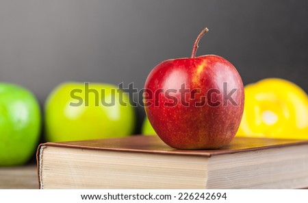 Red apple and book on a table.