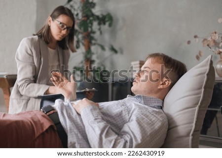 female psychologist conducts psychotherapy session for man. patient in clinic's office on couch talks about his worries and stresses. diagnosis of depression, anxiety disorder. taking care of mental Royalty-Free Stock Photo #2262430919