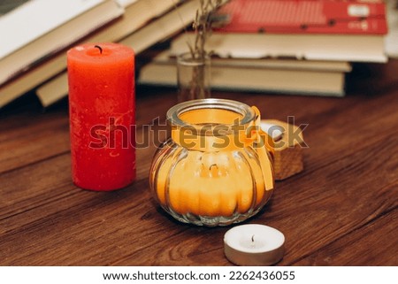 Still life with skins, Orange aroma candle in a figured candlestick with a bow and books on the background.