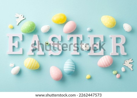Easter concept. Top view photo of word easter colorful eggs and bunnies on isolated pastel blue background