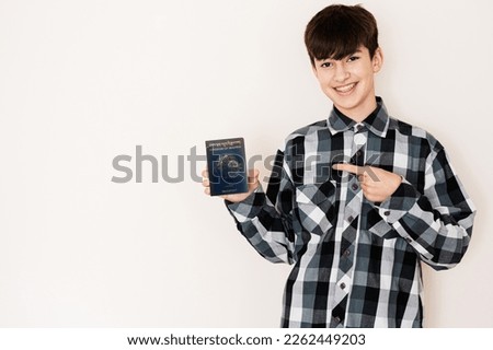Young teenager boy holding Bhutan passport looking positive and happy standing and smiling with a confident smile against white background. Royalty-Free Stock Photo #2262449203