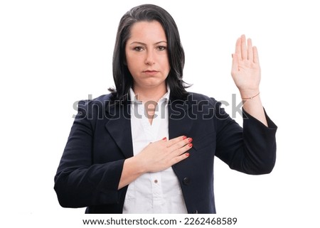 Adult businesswoman in formalwear with serious expression making honest oath gesture touching chest heart isolated on white studio background