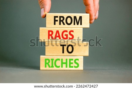 Rags or riches symbol. Concept words From rags to riches on wooden blocks. Beautiful grey table grey background. Businessman hand. Business rags or riches concept. Copy space.