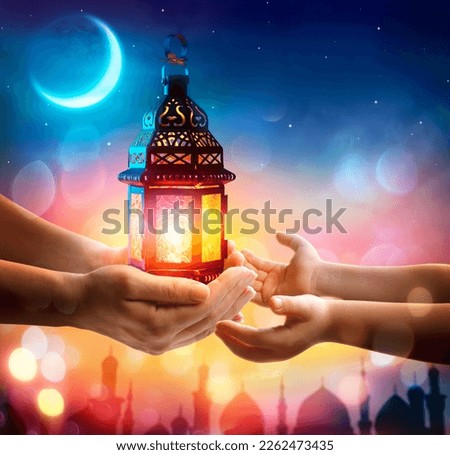 Muslim Holy Month Ramadan Kareem - Hand Give To Kid Arabic Lantern Glowing At Evening With Abstract Defocused Lights - Eid Ul Fitr Royalty-Free Stock Photo #2262473435