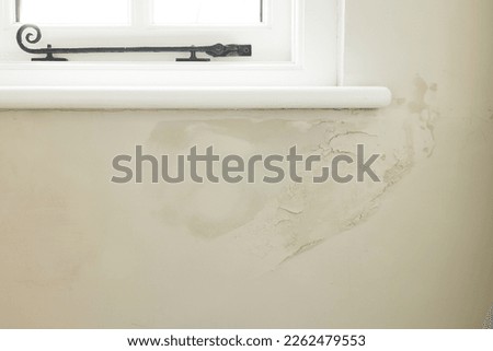 Damp patch under a window of a solid brick wall due to rain penetrating brickwork of old UK house Royalty-Free Stock Photo #2262479553