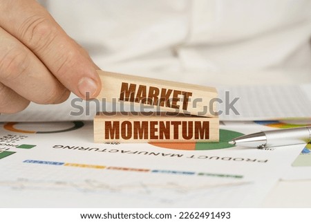 Business concept. On the table are business charts and diagrams in the hands of a wooden block with the inscription - MARKET MOMENTUM