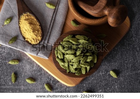 Green cardamom in wooden bowl and spoon. Dry cardamom spice. Cardamom seeds macro shot. Royalty-Free Stock Photo #2262499351