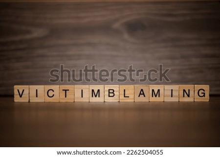 The word victimblaming composed of wooden cubes tablets on a dark wooden background