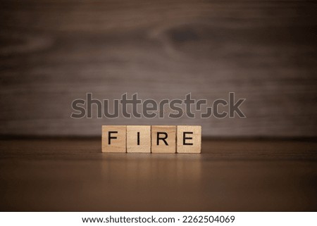 The word fire is made up of wooden cubes tablets on a dark wooden background