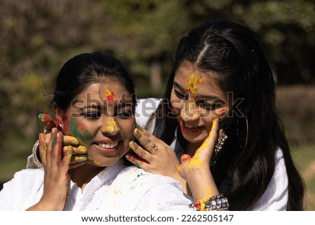 Two young girls sisters friends family celebrating enjoying holi festival of colors colours outdoor in a park a popular hindu festival celebrated across india with gulal abeer color powder