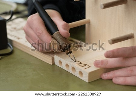 Person burns name with fire Tool in penholder Royalty-Free Stock Photo #2262508929